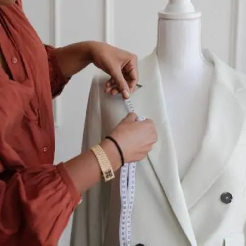 Close-up of a person’s hands buttoning a dark suit jacket, with a wristwatch visible.Double-Breasted Wool Jackets: