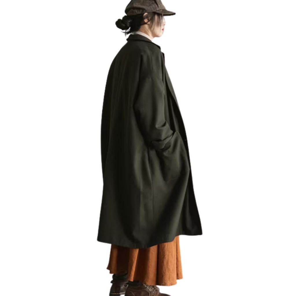A person in side profile wearing a long dark coat, brown skirt, and flat cap against a white background.Is a Long Parka Coat Worth It?