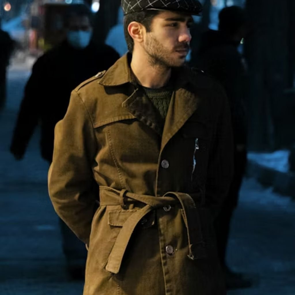 Person wearing a brown coat and patterned cap standing on a city street at night.Trench-Style Winter Coats