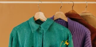 Velvet Overshirt Jacket: A Luxurious Layering Essential Pro Several colorful jackets on wooden hangers hanging on a rack against a warm orange wall.