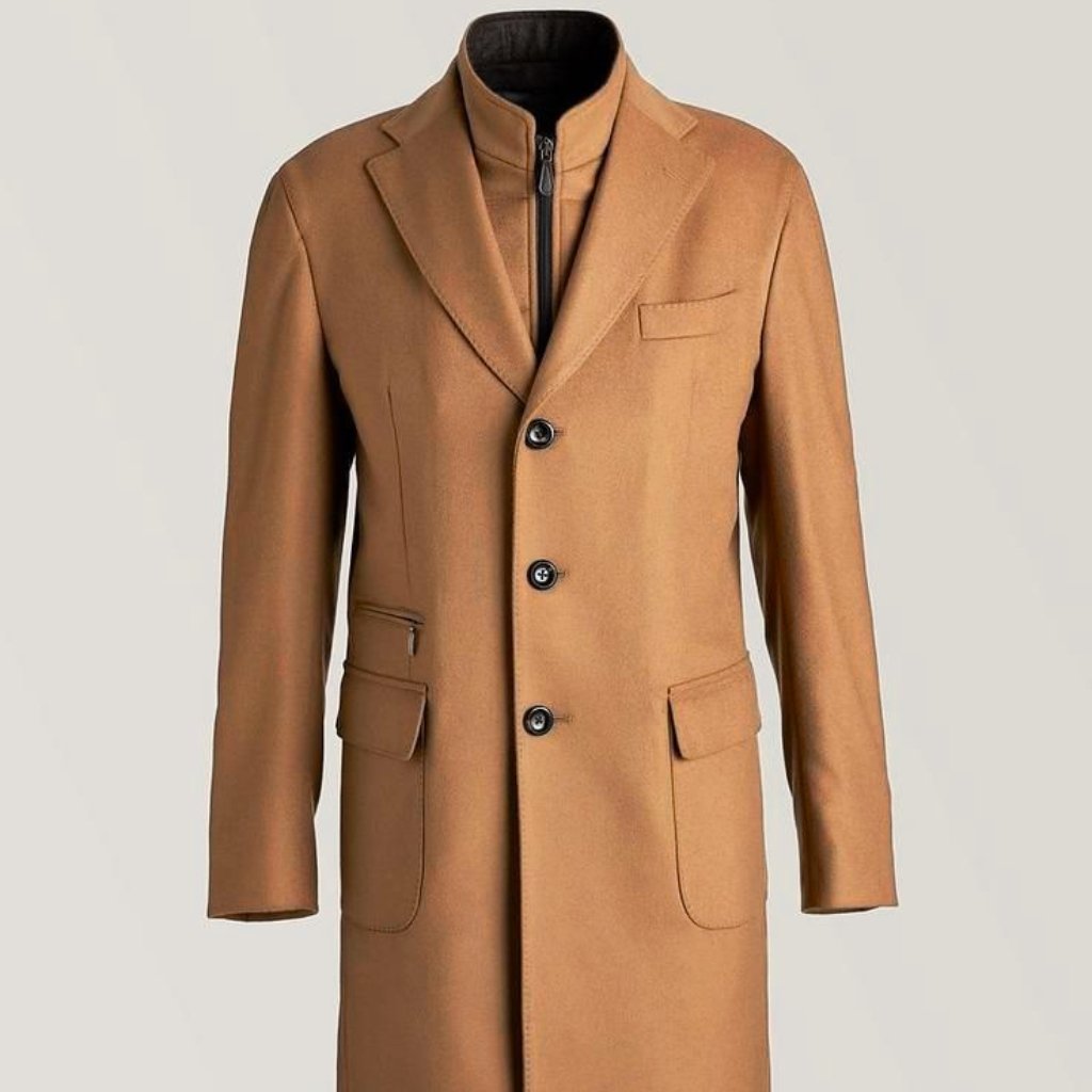 A camel-colored long wool coat with a stand-up collar and a three-button front. It features a single chest pocket, two large front flap pockets, and additional zipper detail at the inner layer. The coat has clean, tailored lines and a modern, sophisticated silhouette.