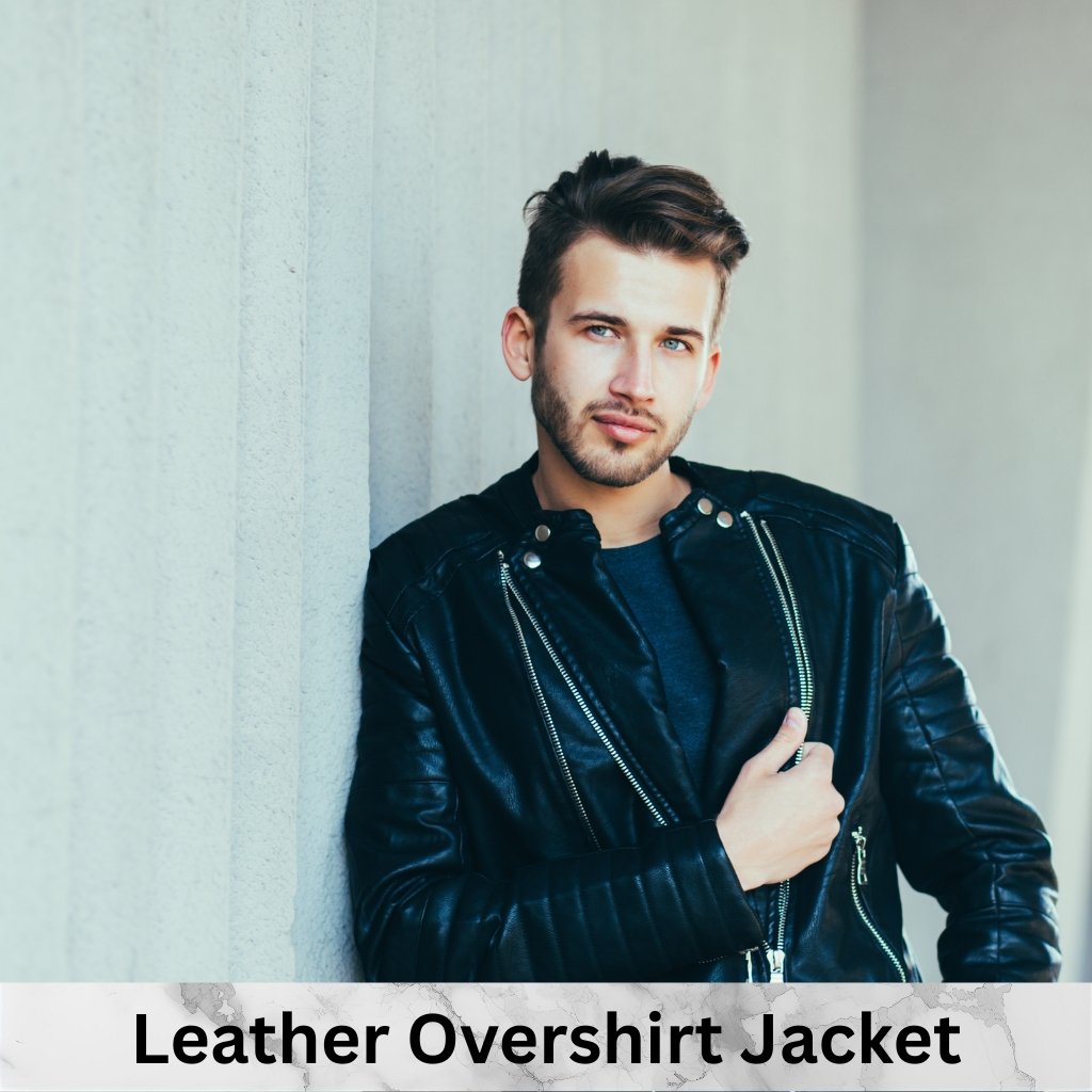 Leather Overshirt Jacket: A Modern Classic for All Seasons 12 A man leaning against a light-colored wall, wearing a black leather overshirt jacket and a dark blue shirt.