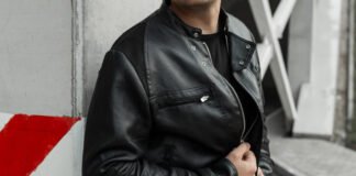 Workwear Field Leather Jacket: Durable Style for Everyday A person wearing a black leather field jacket with a zipper, standing against a concrete wall with red diagonal markings.