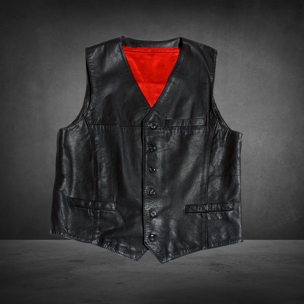 A black leather vest with a red lining, button-front closure, and multiple pockets, displayed against a dark, textured background.