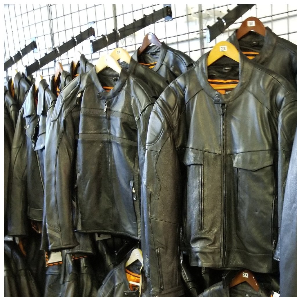 A row of black waxed leather jackets on hangers displayed on a metal rack.