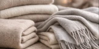 Cashmere Wool Fabric: Features, Uses, Benefits & Care Guide A cozy stack of folded beige and light gray woven blankets, with fringe details on the edge of one blanket. Cashmere Wool Fabric