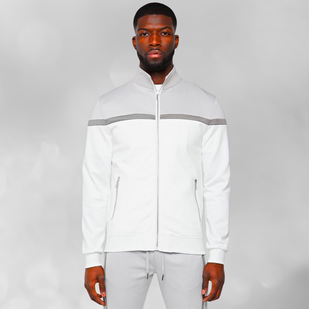 A man wearing a white zip-up jacket with a light gray horizontal stripe across the chest, standing against a soft gray background.