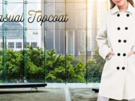 A stylish, minimal black-and-white coat on a model stands in a modern glass-walled lobby with a cityscape visible outside. The text “Casual Topcoat” is written across the window. Casual Topcoat