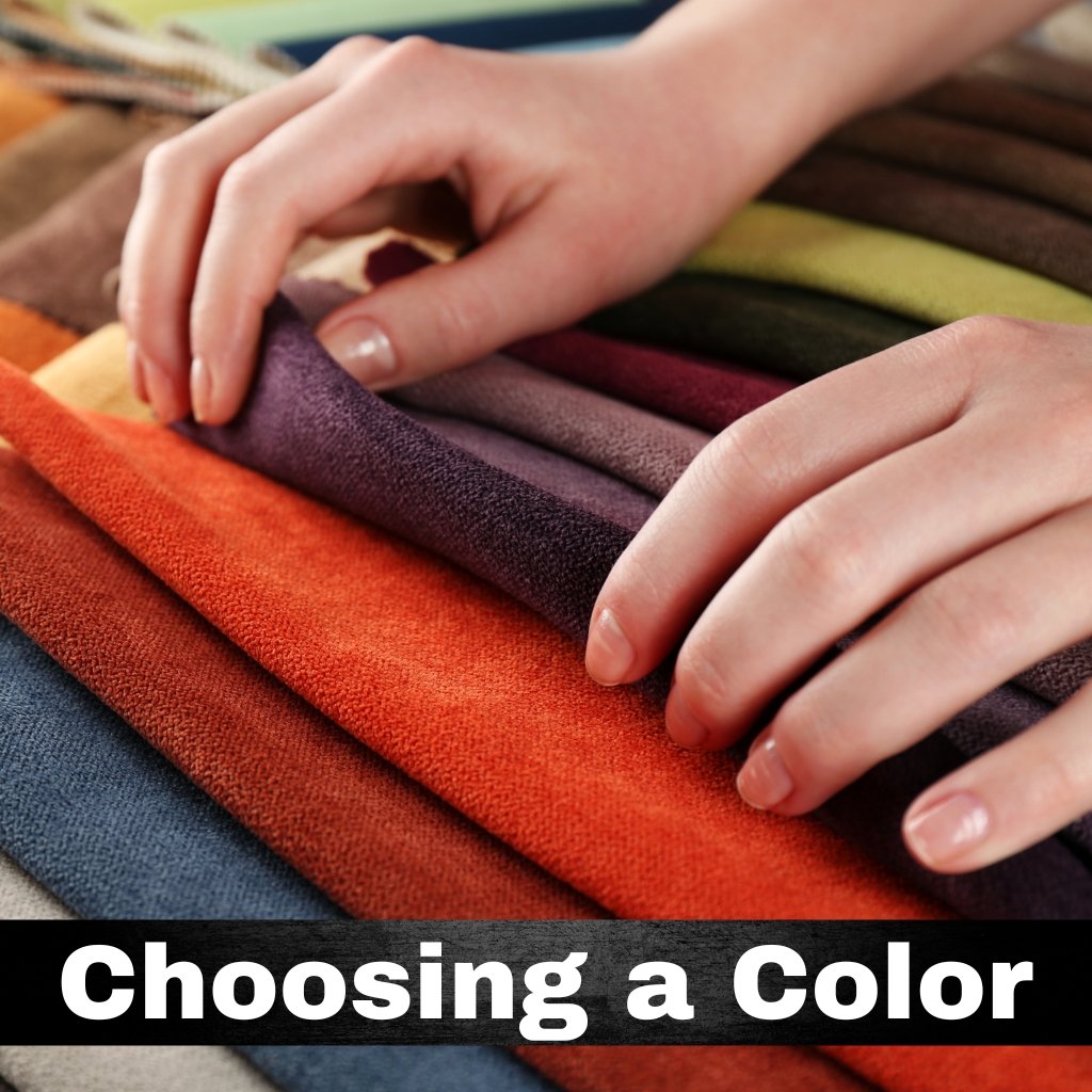 Hands selecting colored fabric swatches arranged in a rainbow of colors.