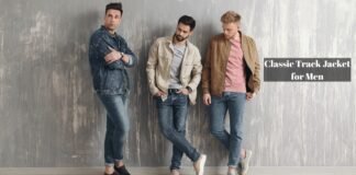Classic Track Jacket for Men Fit, Fabric, and Styling Guide. Three men standing against a textured wall, modeling casual denim and light jackets. One wears a dark denim jacket with rolled cuffs, another sports a light beige jacket over a gray shirt, and the third wears a brown track jacket over a pink shirt. All are in jeans, posing casually. Classic Track Jacket for Men