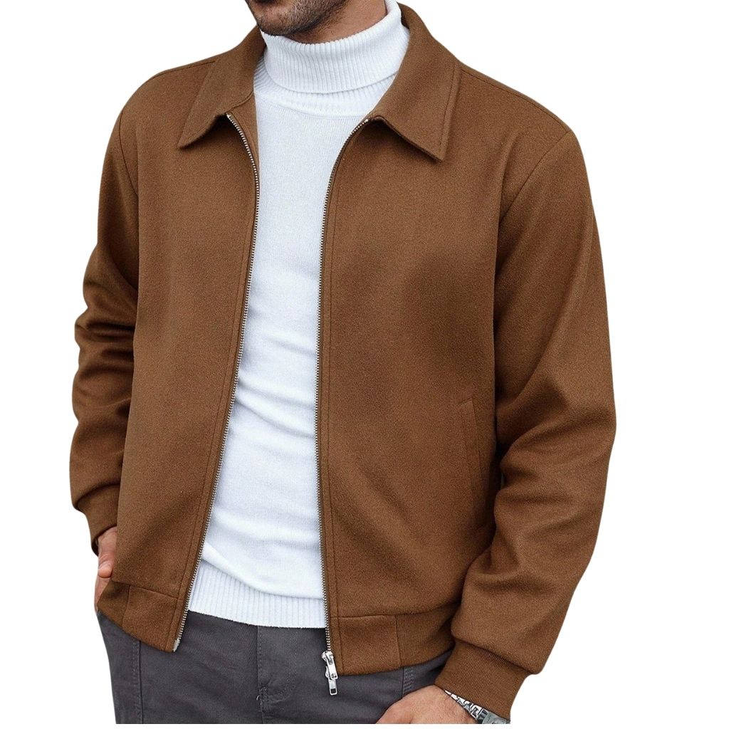 A man wearing a stylish brown zip-front office jacket over a white turtleneck sweater; he poses with one hand in his pocket, showcasing a clean, professional look.