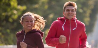 Fleece Hoodie: Cozy, Stylish and Perfect for Every Season Two young people jogging outdoors on a sunny day, woman in a maroon hoodie on the left and man in a bright pink hoodie on the right, both smiling.