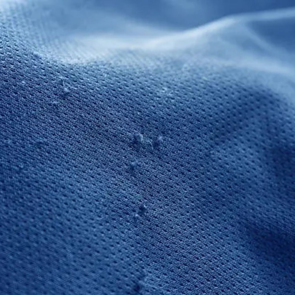 A close-up macro of blue fabric with a fine dotted texture and soft folds.
Moisture-Wicking Winter Fabric Explained:
