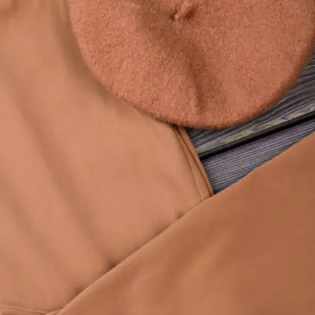 Close-up of a tan-colored fabric with a black-and-gray striped inner layer visible at the seam.Windproof Winter Fabric Material Guide:
