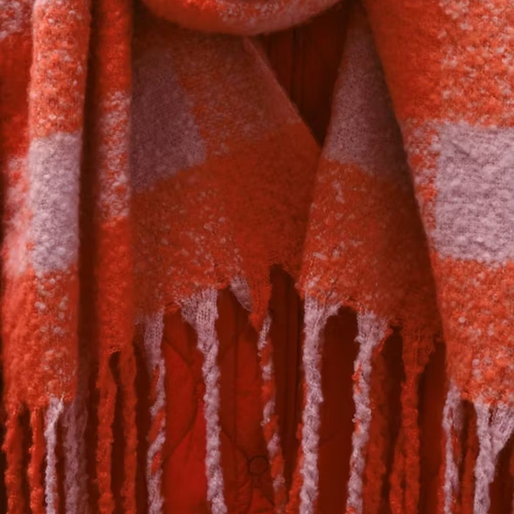“A person sitting on the floor next to a radiator, wrapped in a gray woven blanket with fringe, appears cold.”Wool Thermal Fabric Explained: