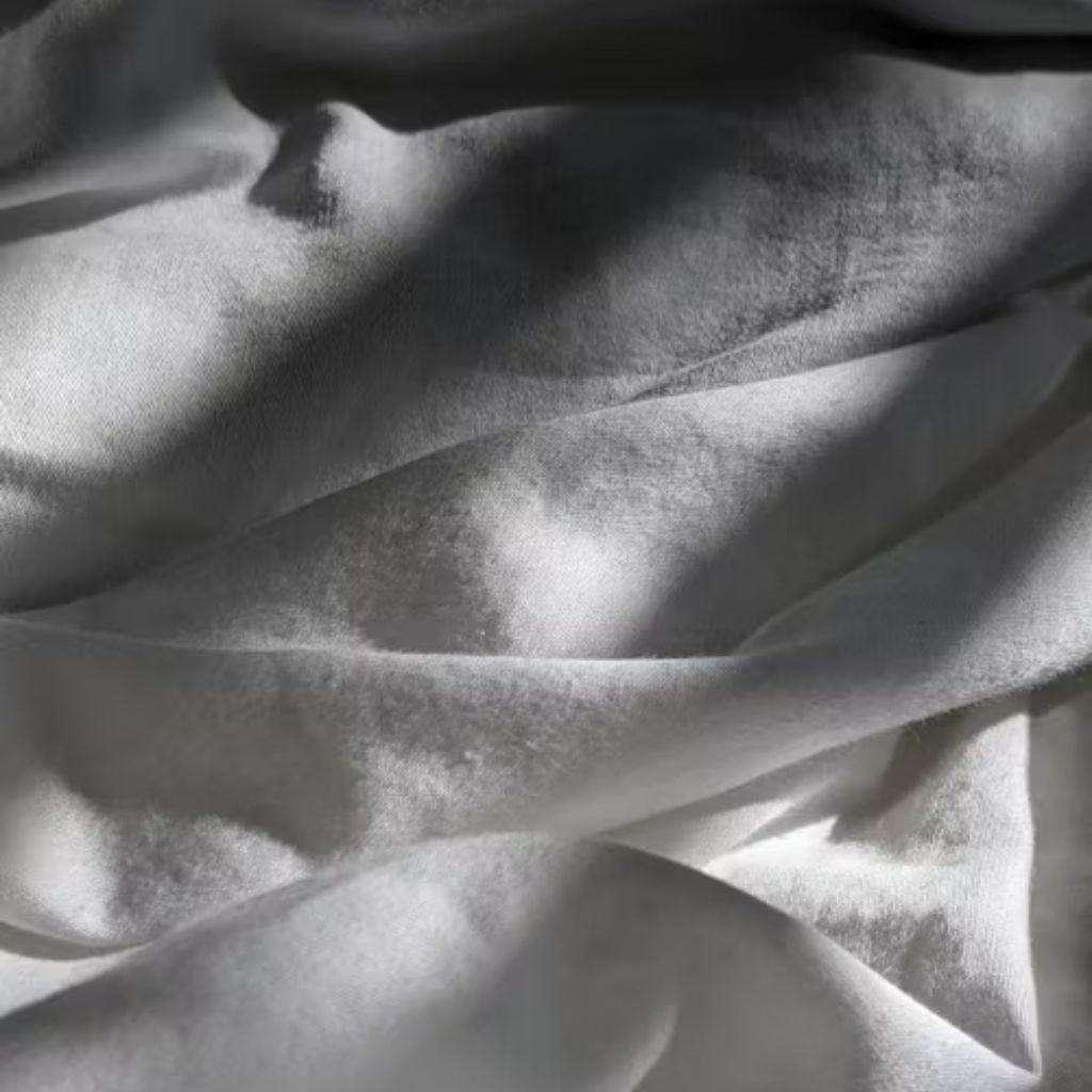 Close-up view of soft white fabric with gentle folds and shadows, suggesting a bedsheet or towel.
Blankets and Bedding fabic