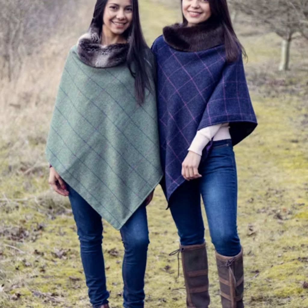 “Two women outdoors wearing oversized plaid ponchos with fur collars, standing side by side on a grassy path.”Wool Thermal Fabric Explained: