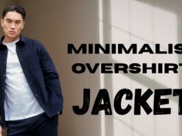 A man wearing a navy minimalist overshirt and white tee stands against a neutral wall.