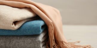 Mongolian Grade A Cashmere Fabric Guide for Luxury Fashion Mongolian Grade A Cashmere Fabric A stack of folded sweaters or blankets in neutral tones (beige, blue, gray) with a peach scarf draped over the top.Mongolian Grade A Cashmere Fabric