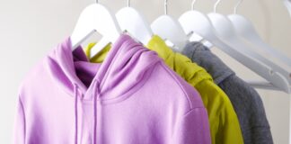 Pullover Hoodie jacket: Comfort, Style & Everyday Wear Guide A lavender hoodie in the foreground, with a yellow raincoat and a grey sweater hanging on white wooden hangers against a neutral beige background.