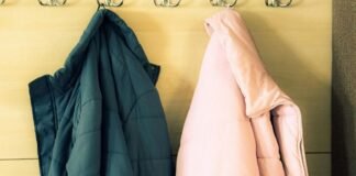 Minimalist Winter Jackets: A Complete Style and Buying Guide Two winter jackets hanging on hooks, one dark teal and one light pink, on a light-colored wooden wall.Minimalist Winter Jackets: