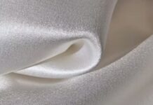 Windproof Winter Fabric Material Guide: Warmth Without Bulk Close-up of smooth, shiny, white satin fabric with soft folds and sheen. Windproof Winter Fabric Material Guide: