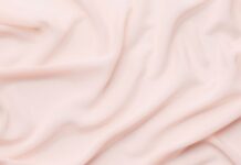 Vegan Winter Fabric Explained: Ethical Warmth Without Wool “Close-up of soft, pale pink fabric with gentle folds and draping.” Vegan Winter Fabric Explained: