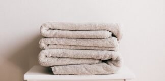 What Is Recycled Wool Fabric? Benefits, Uses, and Care Guide A stack of beige folded towels sits on a white surface against a light, neutral wall.What Is Recycled Wool Fabric?