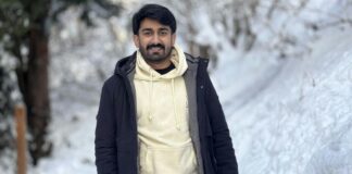 Soft Touch Winter Jacket: Warm, Stylish & Ultra-Comfortable A man with dark hair and a short beard is smiling slightly, wearing a black jacket over a light-colored hoodie. He stands in a snowy landscape with trees in the background. Soft Touch Winter Jacket: