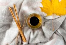 Soft Winter Fabrics for Sensitive Skin: Cozy & Itch-Free Now A cozy flat lay: a cup of coffee, a few cinnamon sticks tied together, and a yellow autumn leaf placed on a soft gray blanket.Soft Winter Fabrics for Sensitive Skin: