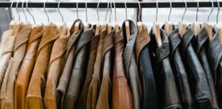 Sports Jackets: Complete Guide to Types, Styles & How to Wear A dense row of leather and suede jackets on a clothing rack, hung on wooden hangers from a black rod. The jackets come in a range of brown and black tones, with subtle textures and stitching visible. The soft lighting highlights the materials, giving a premium, sporty-yet-sophisticated retail vibe. This image features a curated lineup of jackets in earthy browns and blacks, emphasizing varied textures like smooth leather and soft suede. The close packing and warm lighting create a tactile, sporty retail atmosphere, suggesting a premium sportswear or casual outerwear collection. Sports Jackets