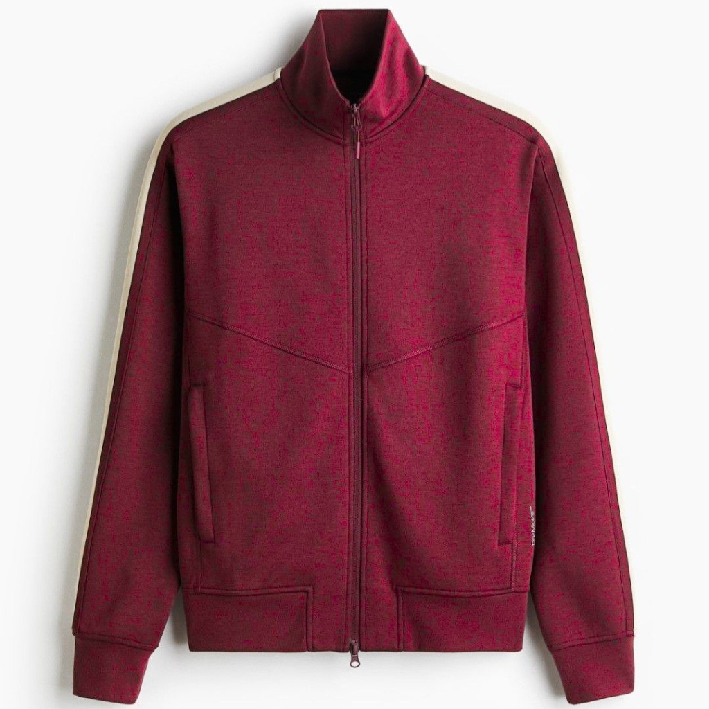 A burgundy zip-up jacket with a high collar and light beige/cream stripe running along the top of the sleeves. Front pockets and ribbed cuffs and hem.