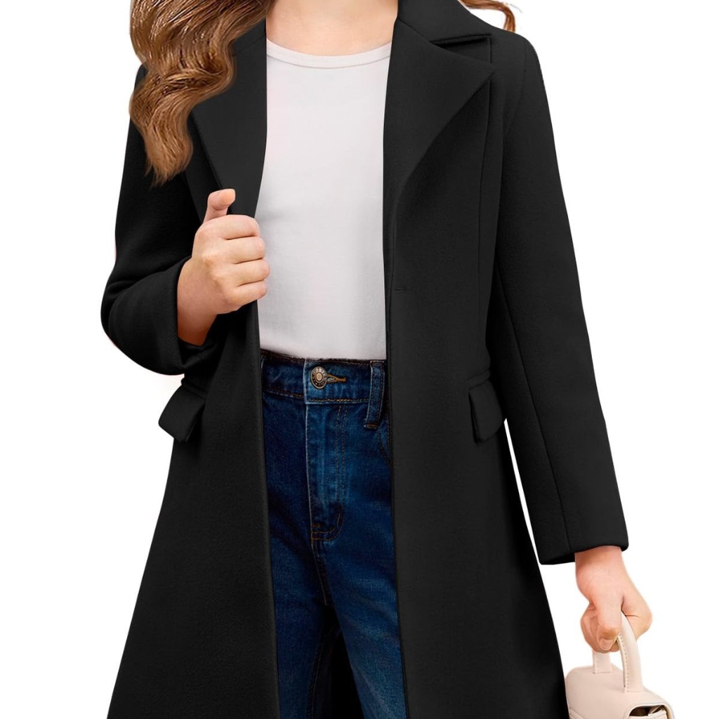  A woman wearing a long black coat over a white top and blue jeans, holding a small light beige handbag.