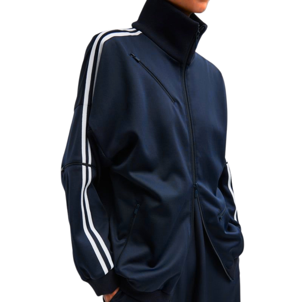 Close-up of a navy blue track jacket with white double stripes along the shoulders and sleeves, a high collar, and zip pockets.