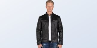 Wilson Leather Jacket: Timeless Style & How to Wear A man wearing a black leather jacket with a stand collar and zippered chest pockets, standing against a light blue background.