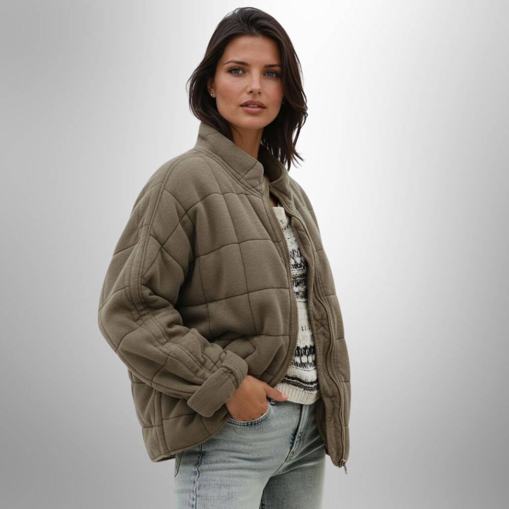 Woman wearing a light brown oversized quilted jacket with a high collar, paired with a patterned knit sweater and light-wash jeans.Cozy Jacket for woman