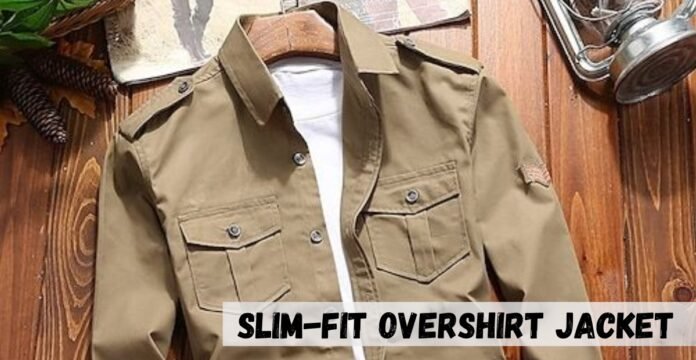 A khaki slim-fit overshirt jacket placed on a wooden surface with a white shirt underneath. The jacket has two chest pockets with flaps and button closures, shoulder epaulets, and a small patch on the left sleeve.