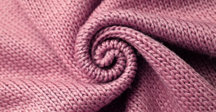Blended Grade B Cashmere Fabric Close-up of a light purple knitted fabric folded into a spiral, showing textured ridges.