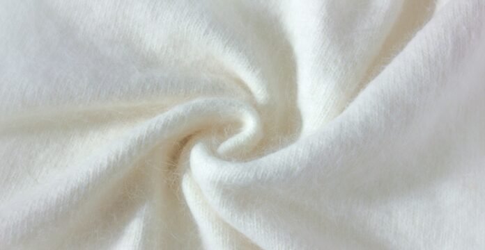 Brushed Grade B Cashmere Fabric Close-up of soft, white cashmere fabric with a swirling, fluffy texture.