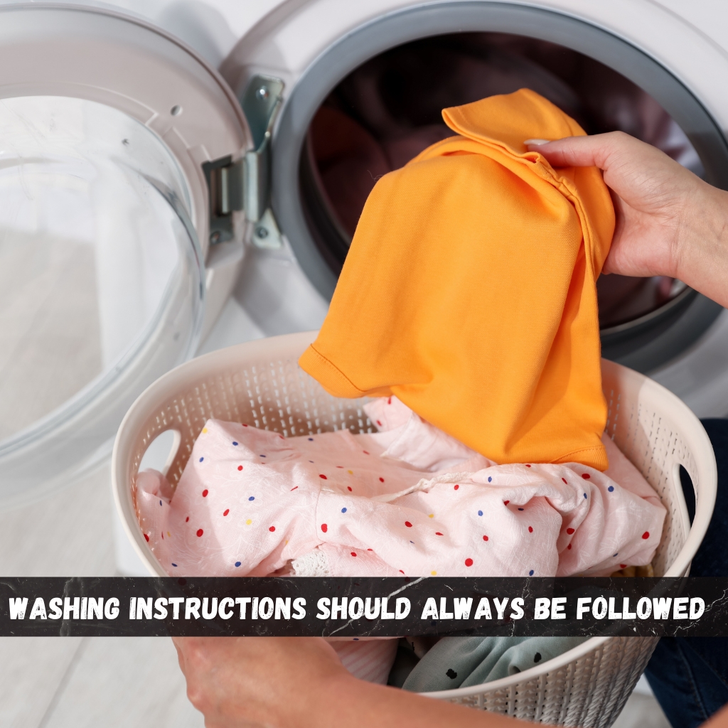 Premium Half-Zip Hoodie for Modern Streetwear Style 6 A person loading a washing machine with clothes, holding an orange shirt over a laundry basket of colorful garments; the washing machine door is open.