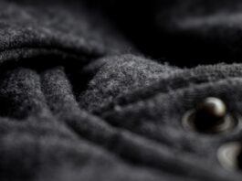Double-Faced Cashmere Fabric Close-up of dark gray cashmere/wool fabric with a soft, textured surface; two metal fasteners on the right side are out of focus.