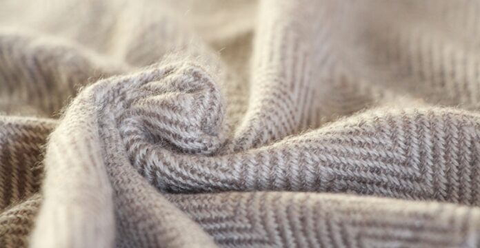 Double-Ply Grade B Cashmere Close-up of folded double-ply cashmere in beige and light gray with a chevron/herringbone pattern.