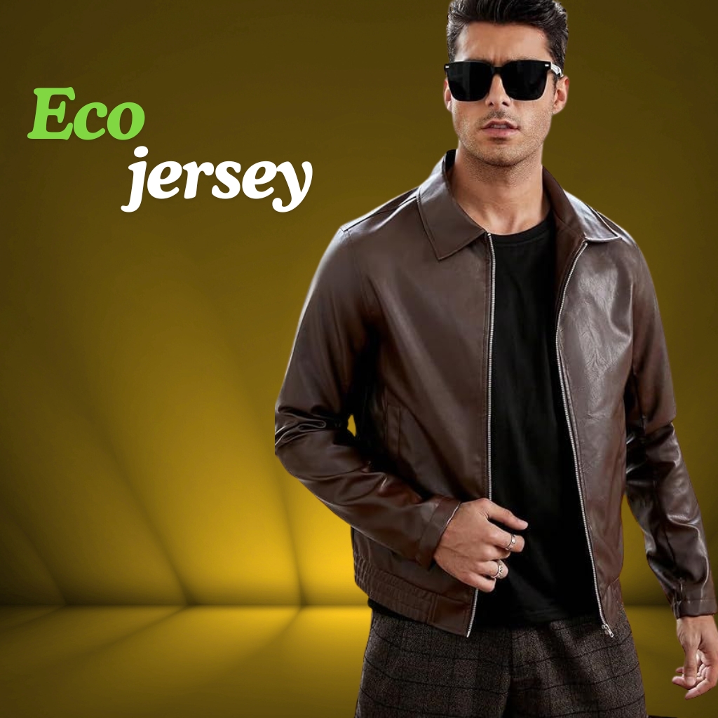 A man wearing a brown matte-finish leather jacket over a black t-shirt, sunglasses, and patterned dark pants, standing against a yellow-brown studio backdrop.