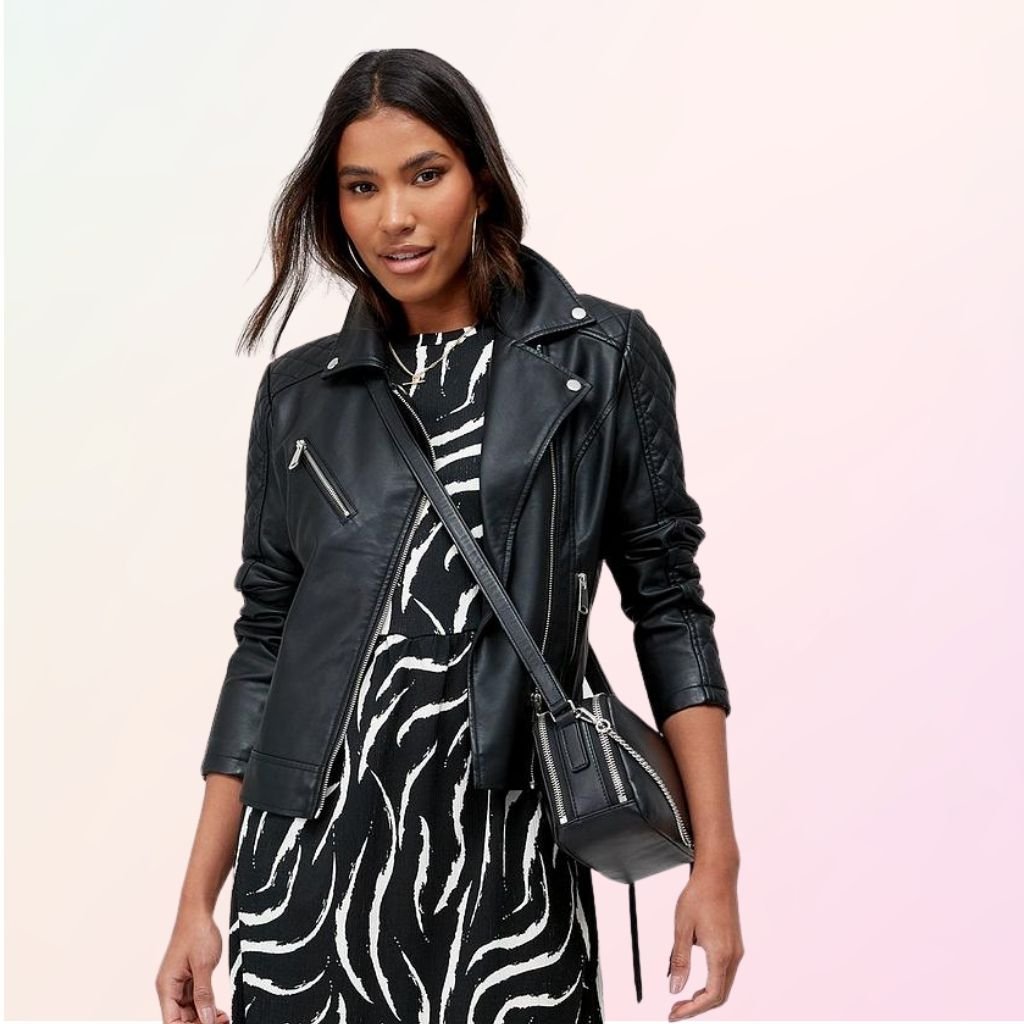 Everyday Leather Jacket – Timeless Comfort and Style for Daily Wear 5 A woman models a black leather jacket over a black-and-white zebra-print dress, with a small black crossbody bag; the background is a soft gradient from white to pink and purple.Everyday Leather Jacket
