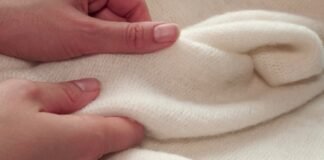 Felted Grade B Cashmere Fabric: Warm & Durable Felted Grade B Cashmere Fabric Close-up of two hands gently holding a soft, off-white felted cashmere fabric with a fuzzy texture.