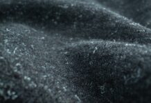 Felted Pure Cashmere Fabric: Features, Uses, and Benefits Felted Pure Cashmere Fabric Close-up of dark gray felted cashmere fabric with small white fibers or lint attached; fabric is draped with soft, fuzzy texture.