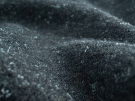 Felted Pure Cashmere Fabric Close-up of dark gray felted cashmere fabric with small white fibers or lint attached; fabric is draped with soft, fuzzy texture.