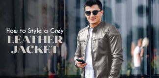 Grey Leather Jacket – Stylish & Versatile Outerwear for Every Look A man wearing a grey leather jacket and sunglasses stands in front of a glass building, holding a smartphone. The words 'How to Style a Grey Leather Jacket' appear on the left.