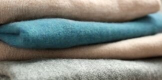 Heavyweight Pure Cashmere Fabric Benefits Heavyweight Pure Cashmere Fabric Close-up of a neat stack of folded heavyweight cashmere sweaters in beige, teal, beige, and gray, with prominent knit textures.
