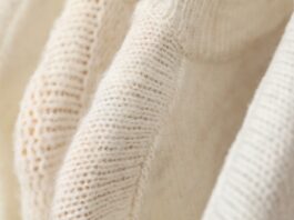 Heavyweight Recycled Cashmere Fabric A close-up of cream-colored heavyweight recycled cashmere fabric, with visible knit texture and soft folds.